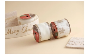Detail of champagne Christmas ribbon with gold Merry Christmas lettering and snowflakes