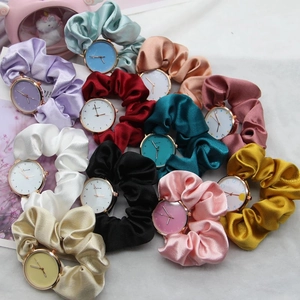 Flat lay of colorful ribbon scrunchie watches in silk textures with golden dials