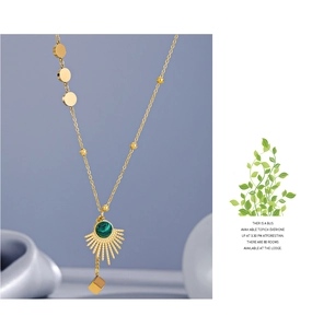 Detailed shot of malachite fan pendant necklace with gold geometric cube on silk fabric