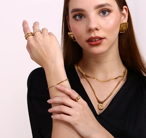 Model wearing gold geometric square earrings with matching necklace and ring set