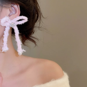 Detail of pink plush bow earrings with snowflake rhinestones and hanging pearls