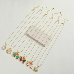 Detail view of gold elephant and pearl pendants arranged on a stone background
