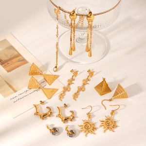 Collection of gold and dual-tone stainless steel geometric earrings on a glass display