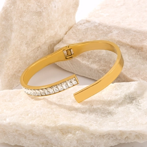 Minimalistischer 18K vergoldeter Armreif mit Zirkonia-Besatz auf Steinen präsentiert