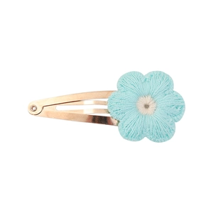 Macro detail of hand-knitted light blue sunflower snap clip with gold metal base