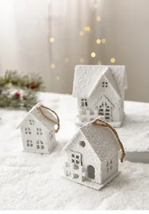Close-up of three white wooden Christmas houses with snowy texture and hemp ropes