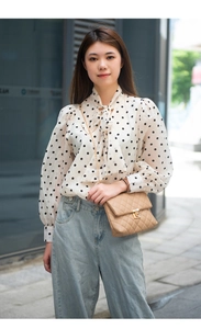 Detail of a beige quilted chain crossbody bag paired with a polka dot blouse
