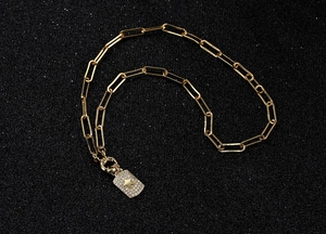 Detailed view of gold paperclip chain necklace with a star-embossed rectangle pendant