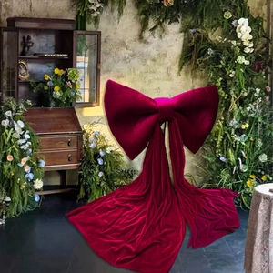 Macro detail of large burgundy velvet decorative bow with long flowing ribbons