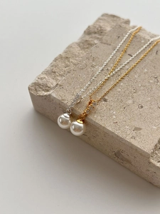 Close-up of S925 silver pearl necklaces with zircon accents on a textured stone block