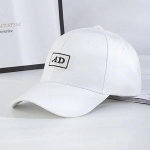 White baseball cap with AD embroidery on a minimalist interior background with books