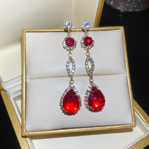Detail of red pear-shaped stone tassel earrings with gold plating and rhinestones