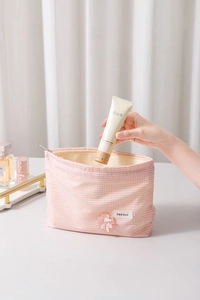 Pink and white gingham makeup bag with flower detail and zipper closure close-up view