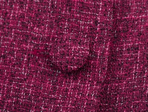 Close-up macro of elegant dark pink tweed fabric texture with matching fabric-covered button