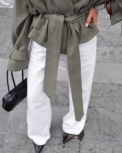 Detail of waist-belt knot on an olive green short trench coat and white pants