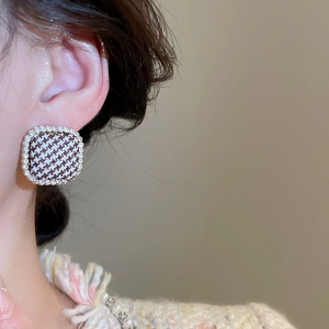 Macro shot of silver stud earrings with houndstooth fabric and sparkling zircon crystals