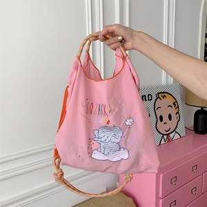 Detail of pink canvas tote featuring cute elephant embroidery and woven shoulder strap