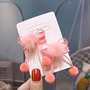 Detail of pink plush ball hair clips with silk bows on a white display card