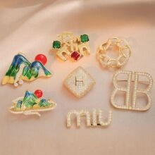 Detailed flat lay of vintage style enamel and pearl brooches on pink fabric