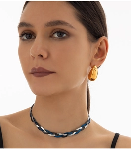 Detail of multi-color braided snake chain necklace and golden teardrop earrings on a model
