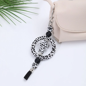 Close-up of a leopard print silicone bead keychain with cross ring and black tassel detail