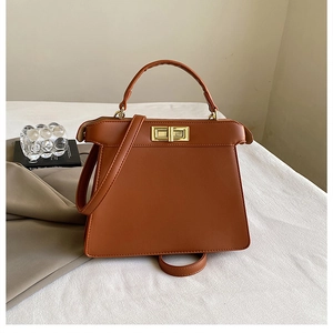 Detailed close-up of a caramel brown woven leather handbag with a gold twist lock closure