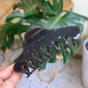 Detail of a large 14cm dark grey translucent shark hair claw clip held by hand