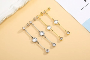 Detailed close-up of gold and silver tassel earrings with three round zircon stones