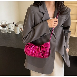 Macro detail of glossy metallic fuchsia cloud bag with elegant pleated texture
