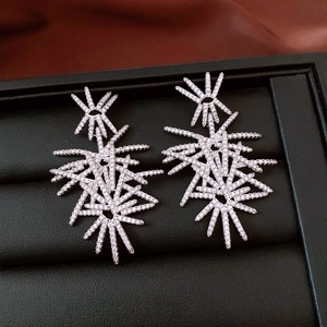 Detailed view of silver starburst earrings with pavé zircons on black leather display