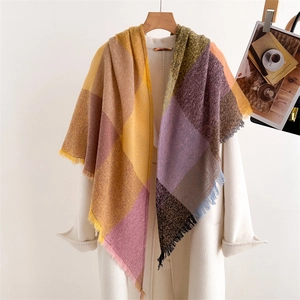Detailed close-up of colorful plaid scarf with soft tassels hanging on a white coat
