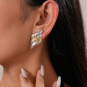 Gros plan de boucles d'oreilles nœud bicolores avec finition métal or et argent sur mannequin