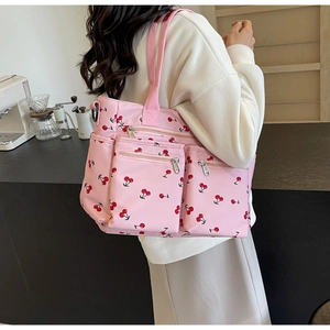 Close-up of pink tote bag with cherry print and multiple functional zipper pockets