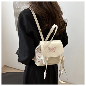 Detail of cream mini backpack with pink butterfly embroidery and floral side panels