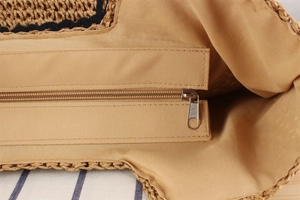 Détail de la doublure en tissu kaki et de la fermeture éclair sur le sac en paille