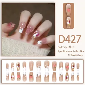 Detail of coffin-shaped press-on nails featuring peach clouds and heart patterns