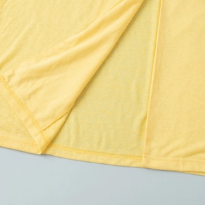 Detailed close-up of double-stitched hem on a vibrant yellow breathable summer fabric