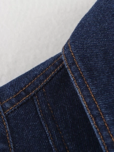 Gros plan sur le tissu denim bleu foncé avec coutures contrastées orange et texture sergée
