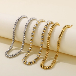 Ensemble de colliers à billes en acier inoxydable doré et argenté sur fond beige doux