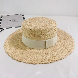 Detail of hand-woven natural raffia texture on a wide-brim boater hat with ribbon