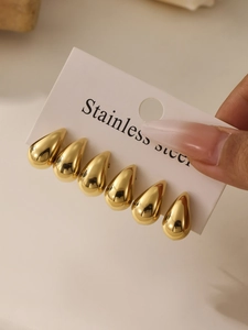 Detailed view of three pairs of polished gold teardrop earrings on a white display card