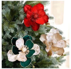 Détail de fleurs de Noël en velours scintillant rouges et dorées sur un sapin festif