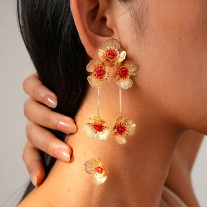 Gros plan détaillé de longues boucles d'oreilles fleuries dorées avec roses rouges