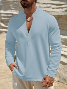 Detail of light blue linen henley shirt with V-neck buttons on a male model at the beach