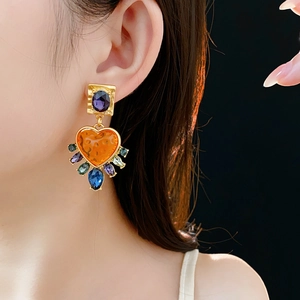 Detail of vintage palace style earrings with purple square and orange heart gemstones