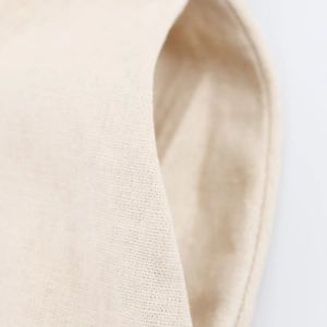 Close-up of oatmeal cotton linen fabric texture and stitching on long button-up shirt dress