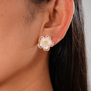 Elegant floral stud earrings in gold and translucent white on a model for daily wear