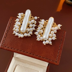 Détail de boucles d'oreilles dorées tressées avec perles blanches sur cuir marron