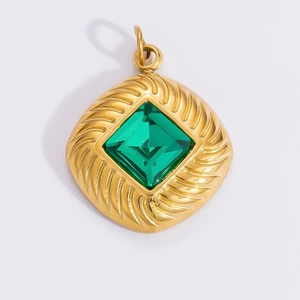 Macro shot of 18k gold butterfly sun pendant with green gemstone and textured frame