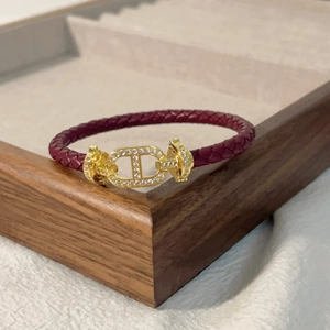 Dettaglio del bracciale in pelle intrecciata bordeaux con chiusura dorata e diamanti